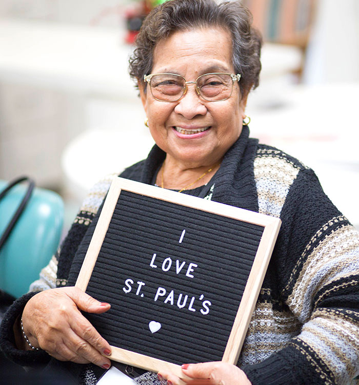 elderly woman holding a sign that says, I love St. Paul's